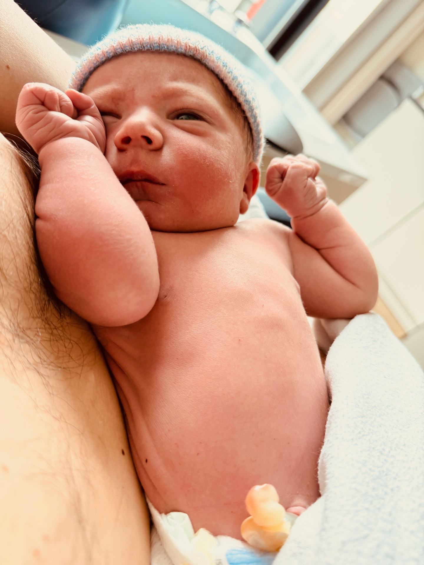 Pasgeboren Pepijn met een gebreid mutsje, in de armen van papa
